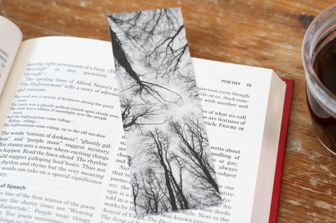 Open book with a black and white tree design bookmark on a wooden surface.