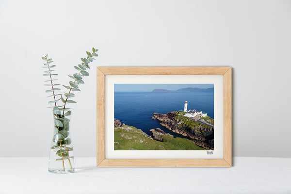 Fanad Lighthouse aerial photograph in a natural frame showing Donegal coastline under a clear blue sky.
